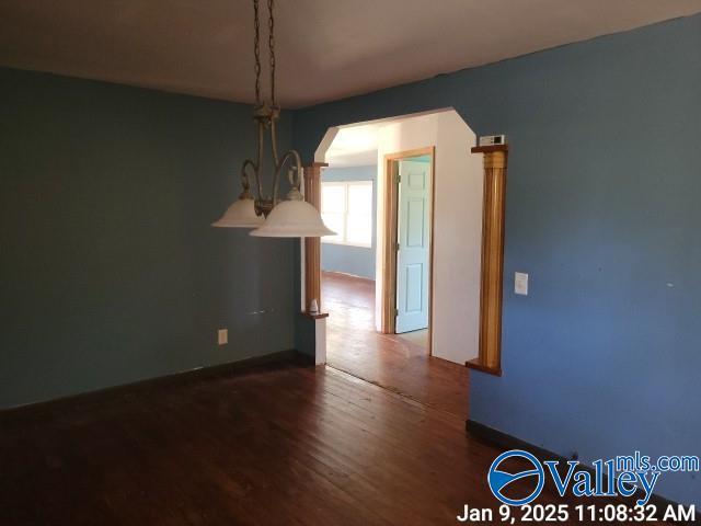 unfurnished dining area featuring a notable chandelier and dark hardwood / wood-style floors