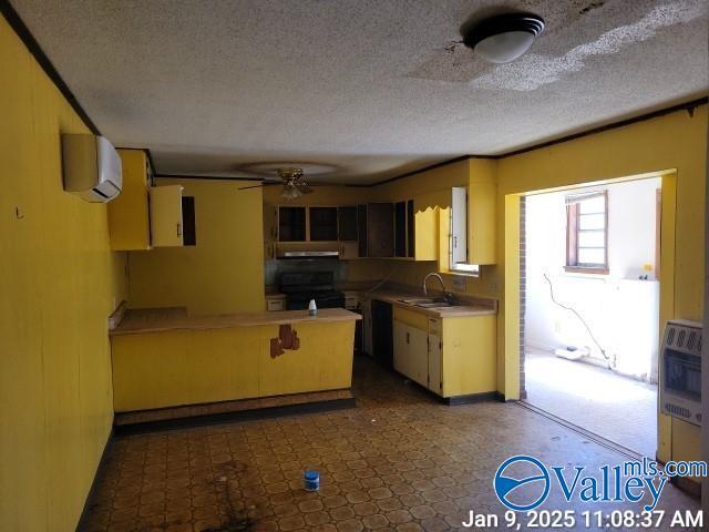 kitchen featuring kitchen peninsula, black stove, heating unit, a wall mounted AC, and ceiling fan