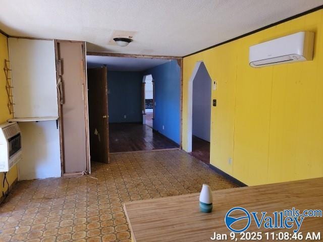 interior space featuring a wall mounted air conditioner, ornamental molding, and heating unit