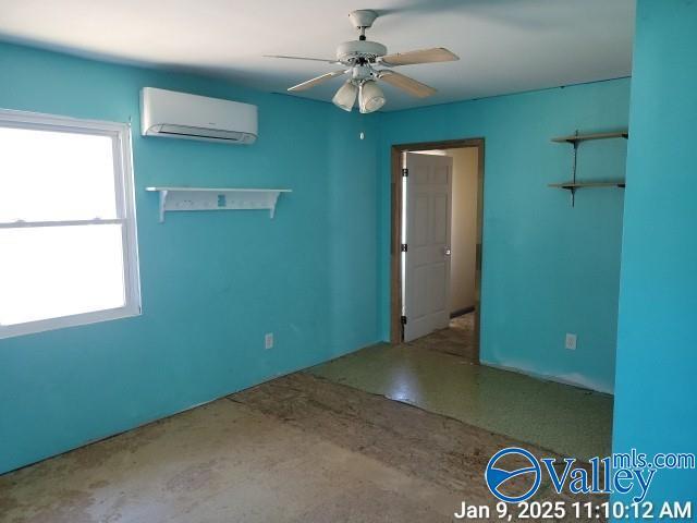 unfurnished room with ceiling fan and a wall mounted AC