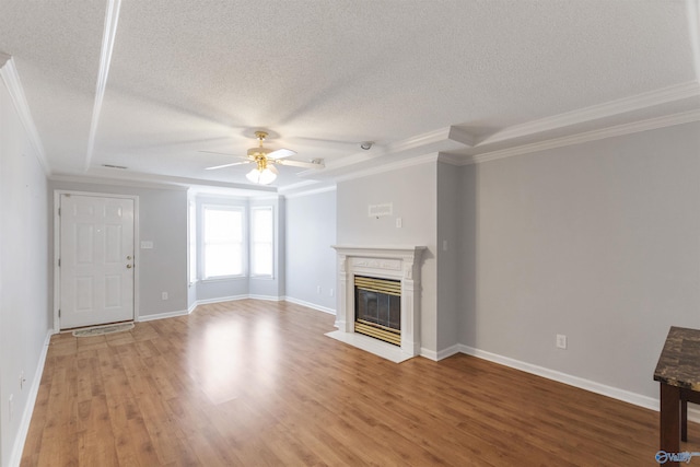 unfurnished living room with ornamental molding, a textured ceiling, a tray ceiling, ceiling fan, and hardwood / wood-style flooring