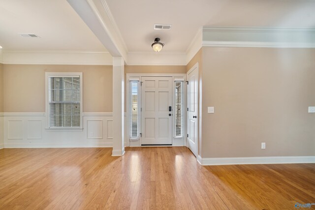 entrance foyer featuring light wood-style floors, wainscoting, visible vents, and crown molding