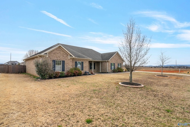 ranch-style house with brick siding, fence, and a front yard