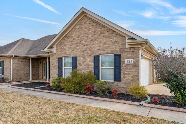 single story home with a garage, driveway, roof with shingles, and brick siding