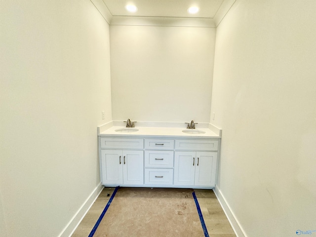 bathroom featuring ornamental molding, a sink, and baseboards