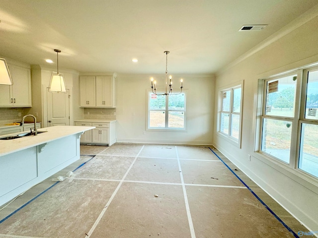 kitchen featuring visible vents, light countertops, white cabinetry, pendant lighting, and a sink