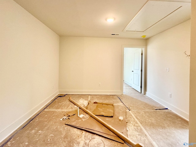 empty room featuring attic access, visible vents, and baseboards