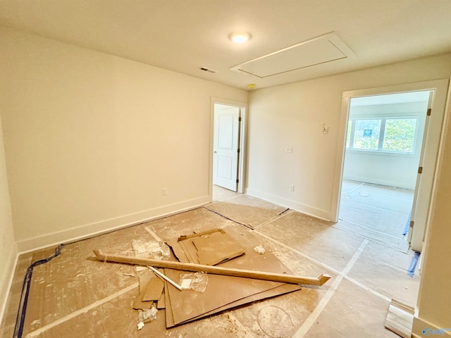 unfurnished room featuring attic access, visible vents, and baseboards