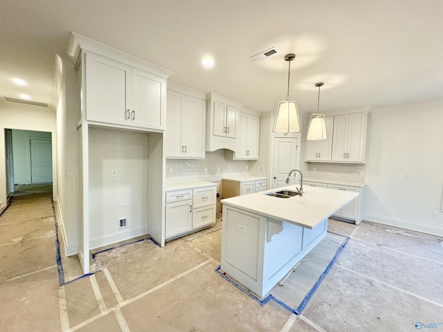 kitchen with a center island with sink, white cabinetry, light countertops, and a sink