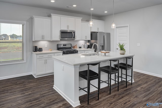 kitchen featuring white cabinetry, dark hardwood / wood-style floors, appliances with stainless steel finishes, and an island with sink