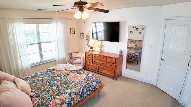 bedroom featuring light carpet, multiple windows, and ceiling fan