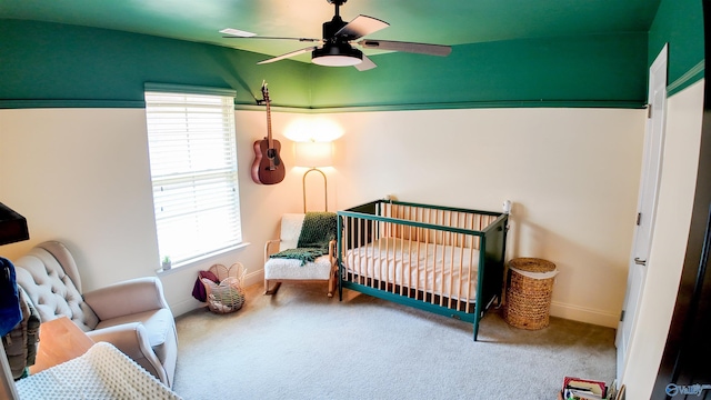 bedroom with ceiling fan, carpet, and a crib