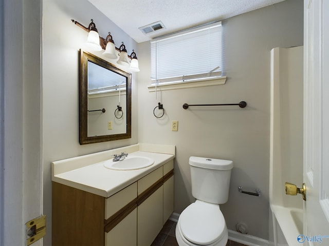 bathroom with toilet, vanity, a textured ceiling, and tile patterned flooring