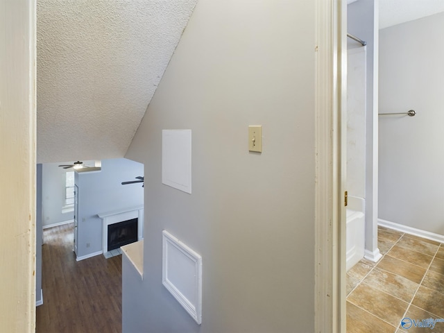 corridor with hardwood / wood-style floors, a textured ceiling, and lofted ceiling