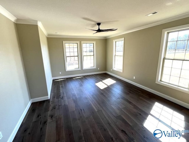 empty room with a wealth of natural light, visible vents, dark wood-type flooring, and crown molding