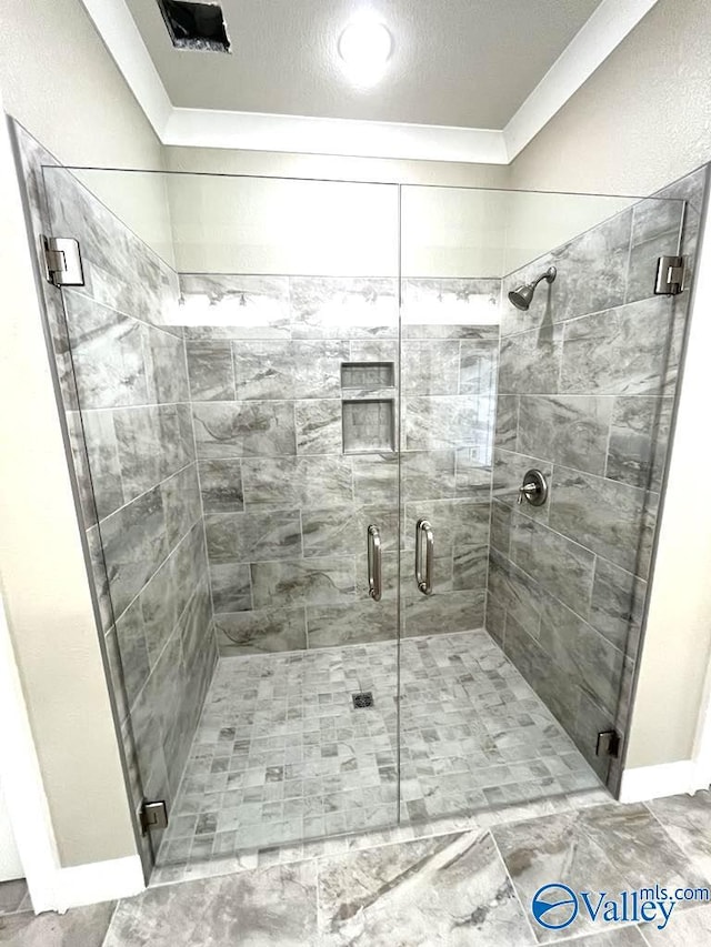 bathroom with a stall shower and crown molding