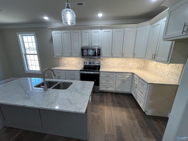 kitchen with light stone counters, stainless steel appliances, a sink, white cabinetry, and decorative light fixtures