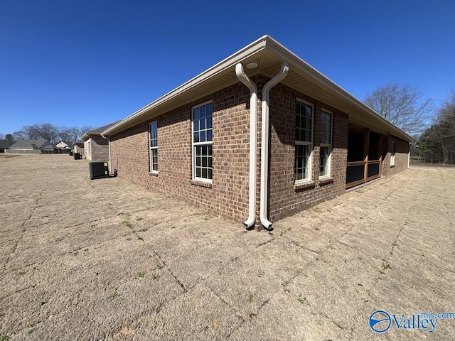 view of side of home with brick siding and central AC