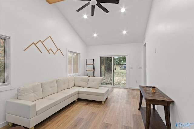 living room with light hardwood / wood-style floors, high vaulted ceiling, and ceiling fan