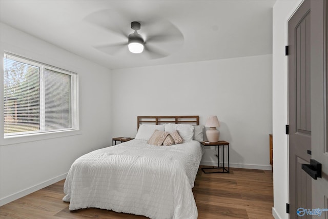 bedroom with ceiling fan, multiple windows, and hardwood / wood-style floors