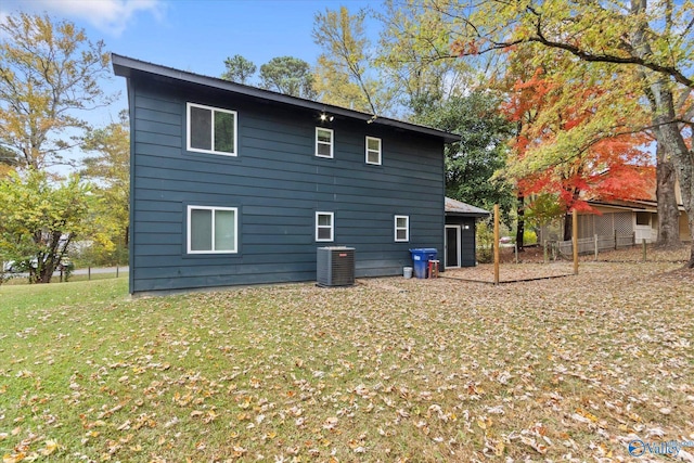 rear view of property with central air condition unit and a yard