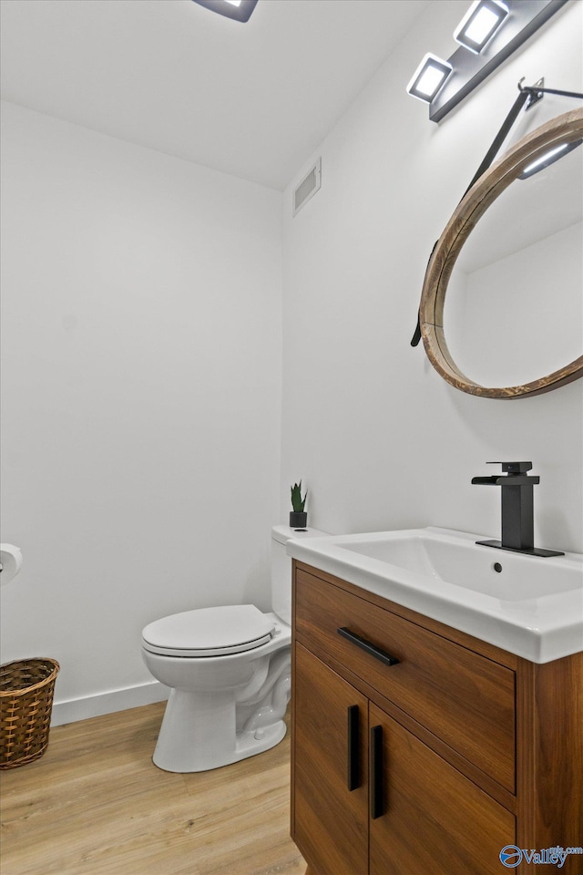 bathroom with toilet, hardwood / wood-style flooring, and vanity