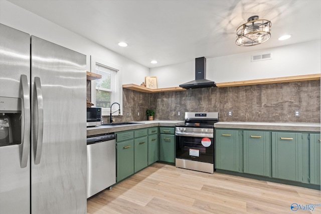 kitchen featuring wall chimney range hood, light hardwood / wood-style flooring, sink, stainless steel appliances, and green cabinetry