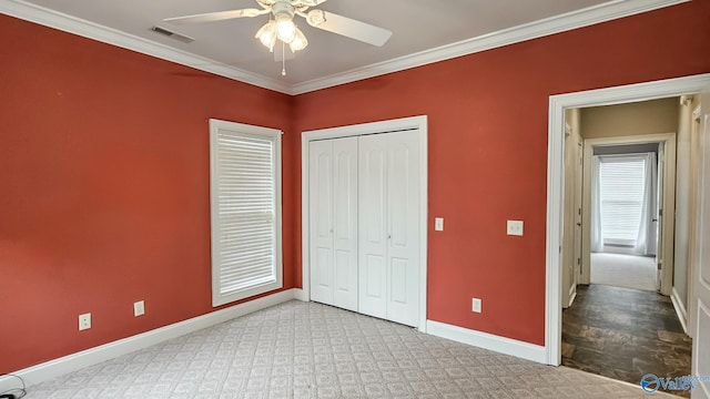 unfurnished bedroom featuring crown molding, a closet, baseboards, visible vents, and ceiling fan