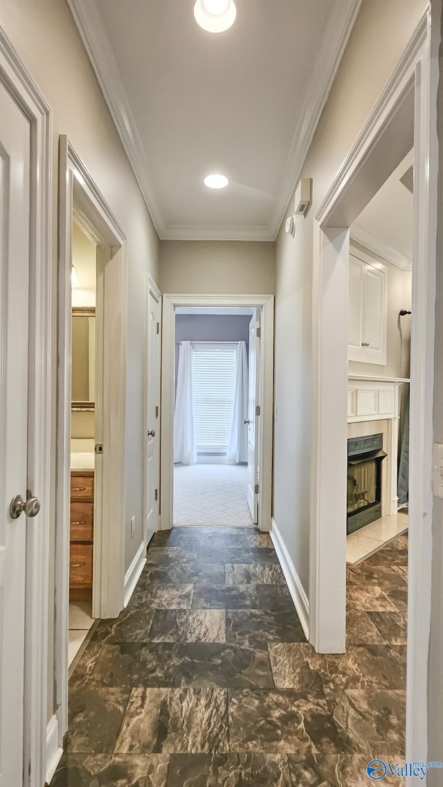 hall with marble finish floor, baseboards, and ornamental molding