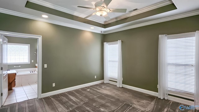 empty room with visible vents, baseboards, ornamental molding, a ceiling fan, and a tray ceiling