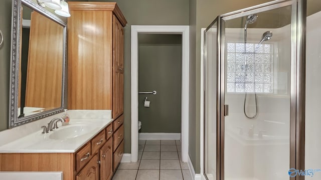 full bath featuring tile patterned flooring, vanity, toilet, baseboards, and a stall shower