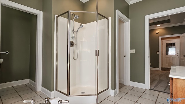 bathroom with tile patterned flooring, ornamental molding, baseboards, and a shower stall