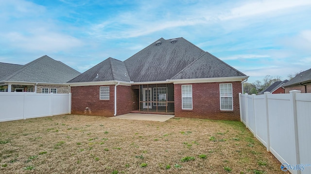 rear view of property with brick siding, a fenced backyard, a yard, and a patio area