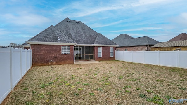 back of property featuring a fenced backyard, brick siding, roof with shingles, and a lawn