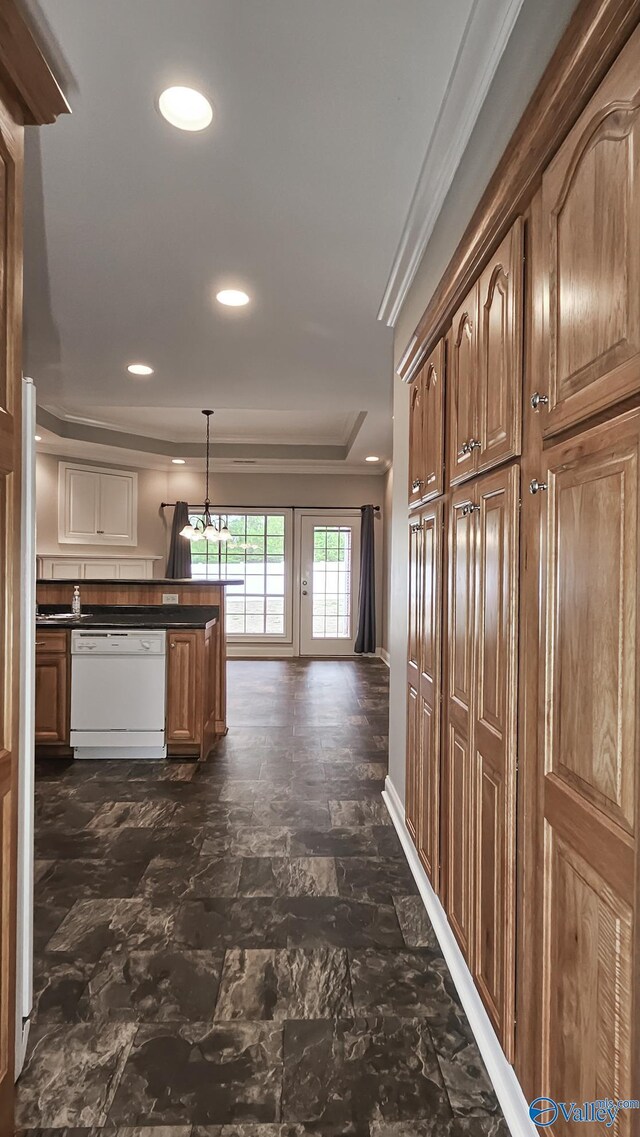 kitchen featuring a raised ceiling, dishwasher, dark countertops, ornamental molding, and recessed lighting
