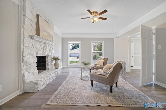 1816 Devonshire Dr SE, Decatur, AL 35601 - living room with ceiling fan, baseboards, a stone fireplace, wood finished floors, and crown molding