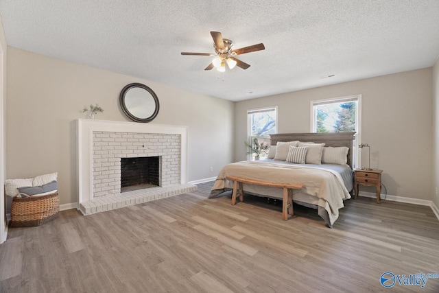 1816 Devonshire Dr SE, Decatur, AL 35601 - bedroom with light wood-type flooring, baseboards, a textured ceiling, a fireplace, and a ceiling fan