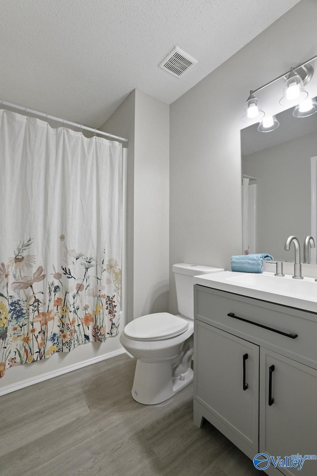 1816 Devonshire Dr SE, Decatur, AL 35601 - bathroom featuring wood finished floors, vanity, toilet, shower / bath combination with curtain, and a textured ceiling