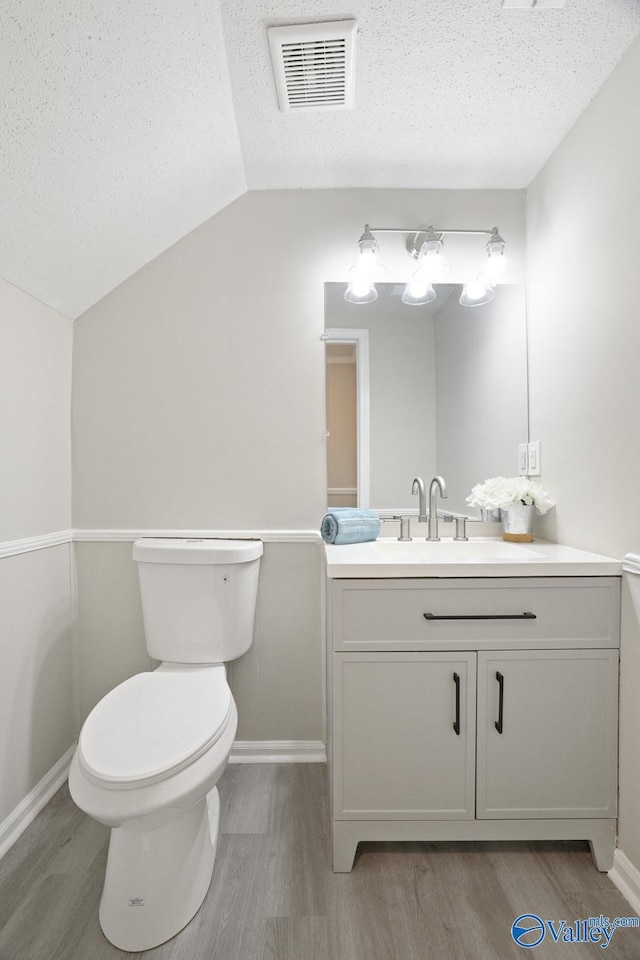 1816 Devonshire Dr SE, Decatur, AL 35601 - half bath featuring wood finished floors, toilet, vanity, lofted ceiling, and a textured ceiling