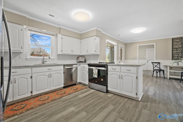 1816 Devonshire Dr SE, Decatur, AL 35601 - kitchen with appliances with stainless steel finishes, a sink, light wood finished floors, a peninsula, and ornamental molding
