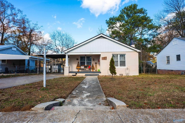 bungalow with a carport, covered porch, and a front lawn