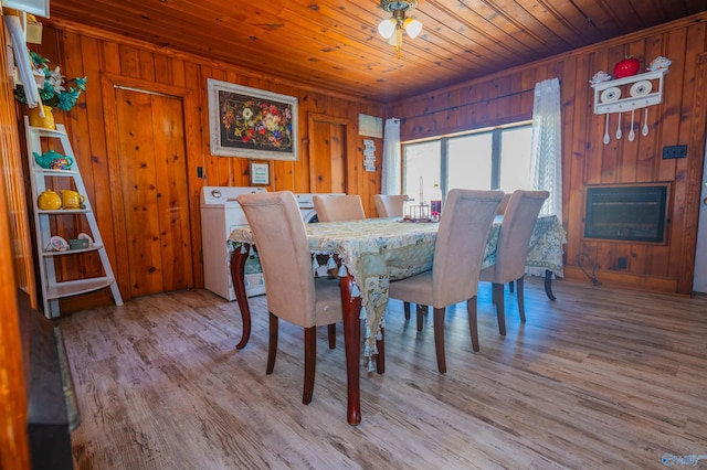 dining space featuring light hardwood / wood-style floors, washing machine and dryer, wood ceiling, and wooden walls