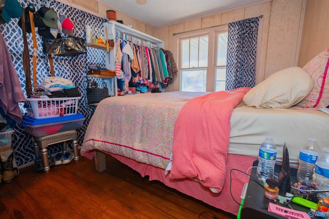 bedroom with dark wood-type flooring and wooden walls