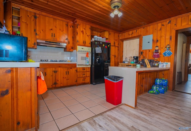 kitchen with oven, black fridge, tasteful backsplash, light hardwood / wood-style floors, and kitchen peninsula