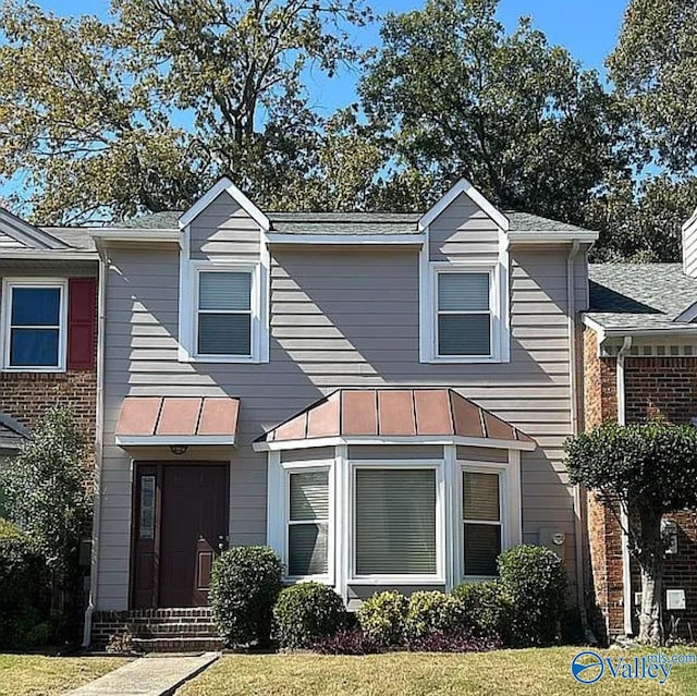 view of front facade featuring entry steps, a standing seam roof, metal roof, and a front lawn