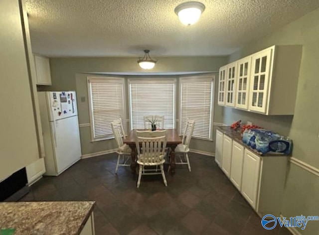 dining space featuring a textured ceiling and baseboards