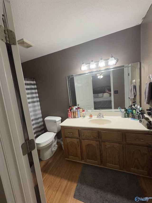 bathroom with hardwood / wood-style flooring, vanity, a textured ceiling, and toilet