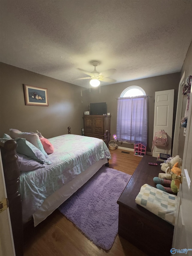 bedroom with hardwood / wood-style floors, a textured ceiling, and ceiling fan