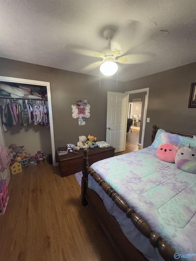 bedroom with wood-type flooring, a textured ceiling, ceiling fan, and a closet