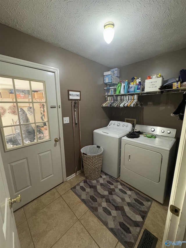 washroom featuring separate washer and dryer, light tile patterned floors, and a textured ceiling